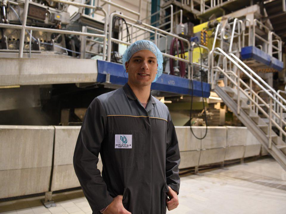 Worker in a hair mask looking at camera in front of machinery